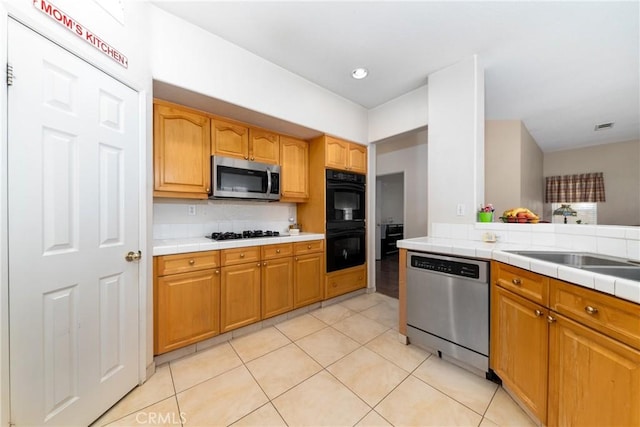 kitchen featuring tile countertops, decorative backsplash, light tile patterned floors, visible vents, and black appliances