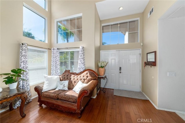 foyer entrance with wood-type flooring, recessed lighting, baseboards, a towering ceiling, and visible vents