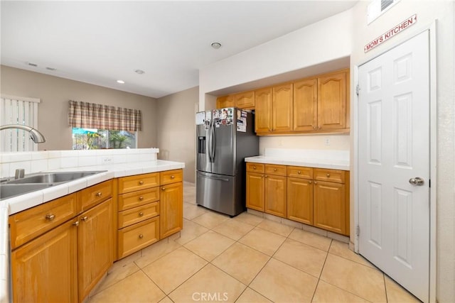 kitchen featuring stainless steel refrigerator with ice dispenser, a sink, brown cabinets, and light tile patterned flooring