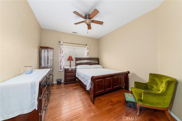 bedroom with baseboards, ceiling fan, visible vents, and wood finished floors