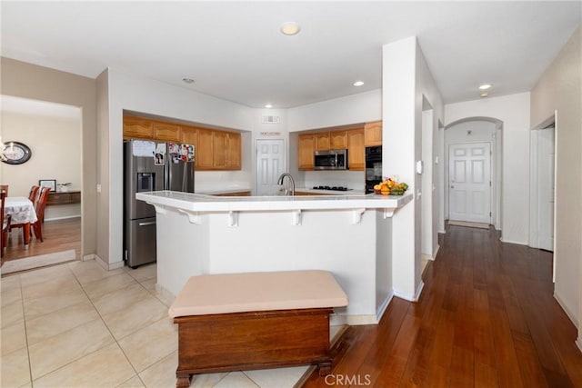 kitchen with visible vents, a peninsula, recessed lighting, tile countertops, and black appliances
