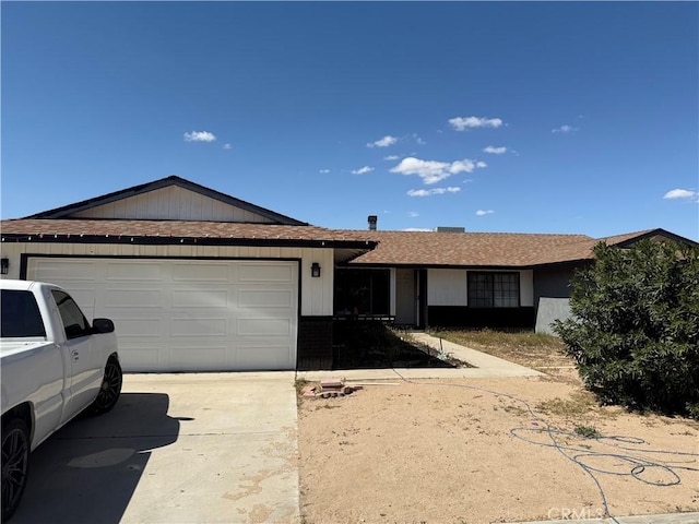 ranch-style home with a shingled roof, an attached garage, and concrete driveway