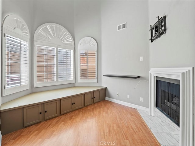 4301 Fulton Ave Unit 303, Sherman Oaks, CA 91423 - unfurnished living room featuring a tile fireplace, plenty of natural light, a high ceiling, light wood finished floors, and baseboards