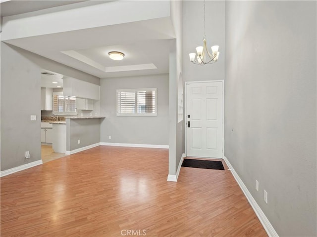 4301 Fulton Ave Unit 303, Sherman Oaks, CA 91423 - foyer featuring a chandelier, a raised ceiling, light wood-style floors, and baseboards