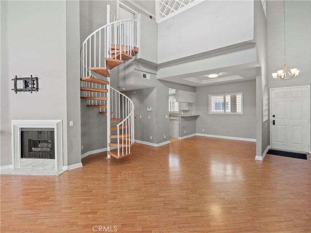4301 Fulton Ave Unit 303, Sherman Oaks, CA 91423 - unfurnished living room featuring a chandelier, wood finished floors, a towering ceiling, baseboards, and stairs