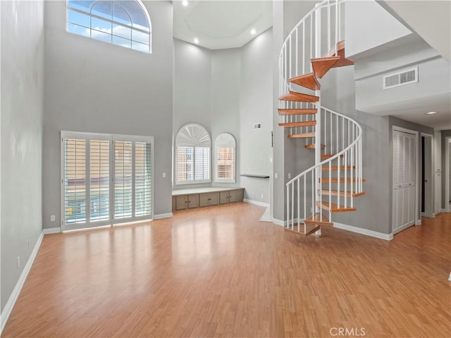4301 Fulton Ave Unit 303, Sherman Oaks, CA 91423 - unfurnished living room featuring a towering ceiling, baseboards, wood finished floors, and stairway