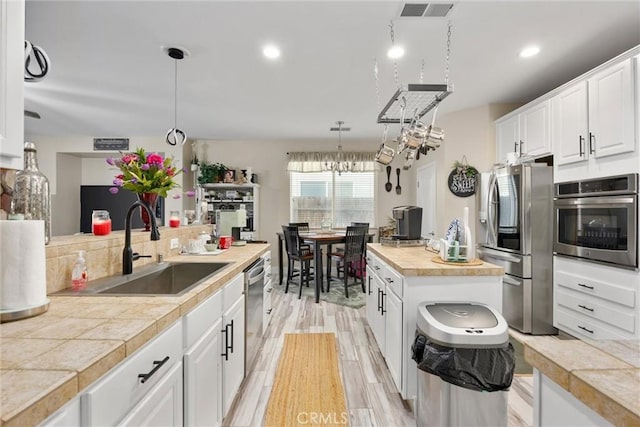 kitchen featuring visible vents, pendant lighting, a sink, white cabinets, and stainless steel appliances