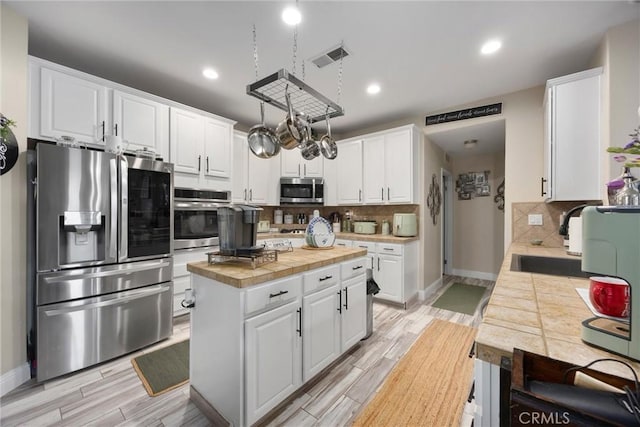 kitchen featuring backsplash, stainless steel appliances, white cabinetry, and a sink