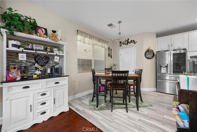 dining area with an inviting chandelier, baseboards, wood finished floors, and visible vents
