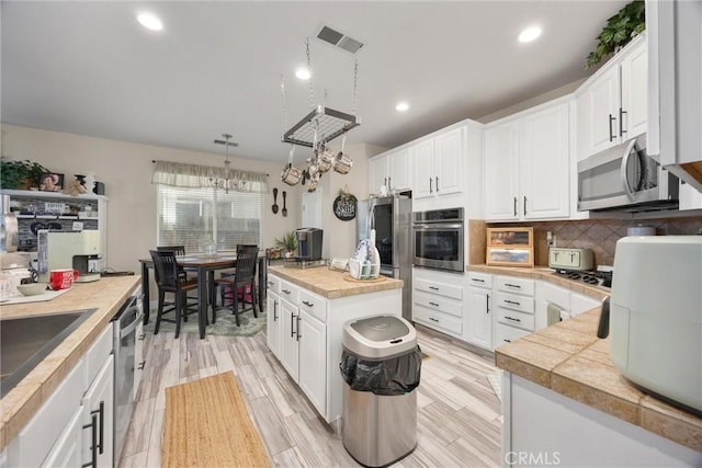 kitchen with visible vents, decorative backsplash, white cabinetry, and appliances with stainless steel finishes