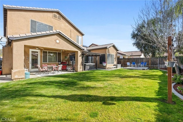 rear view of house with fence, a pergola, a patio, stucco siding, and a yard