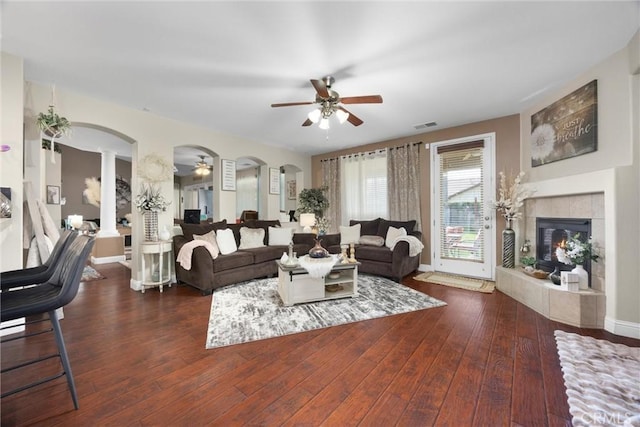 living area featuring visible vents, decorative columns, ceiling fan, hardwood / wood-style flooring, and a tile fireplace