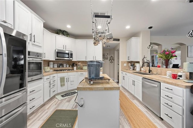 kitchen with decorative backsplash, a center island, light countertops, a sink, and appliances with stainless steel finishes
