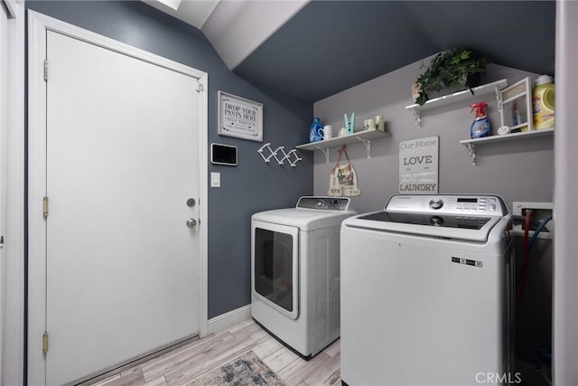 washroom with baseboards, laundry area, washer and clothes dryer, and light wood-style flooring