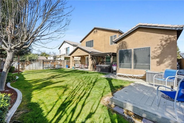 rear view of house with a pergola, a hot tub, stucco siding, a fenced backyard, and a lawn