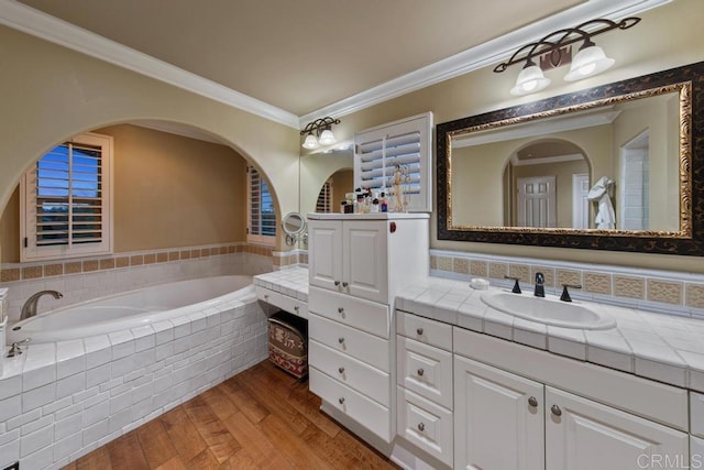 bathroom featuring vanity, ornamental molding, a bath, and wood finished floors