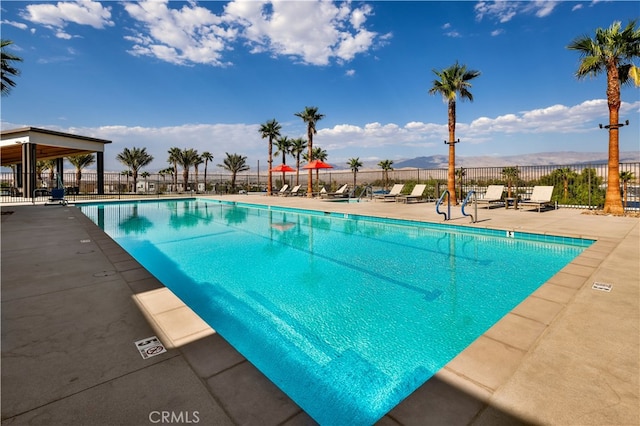 pool with fence, a mountain view, and a patio area