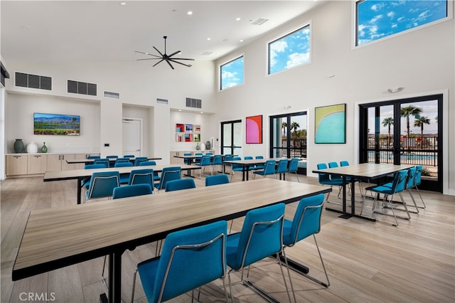 dining room featuring light wood-style floors, a high ceiling, and visible vents