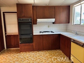 kitchen with a sink, white appliances, light countertops, decorative backsplash, and under cabinet range hood