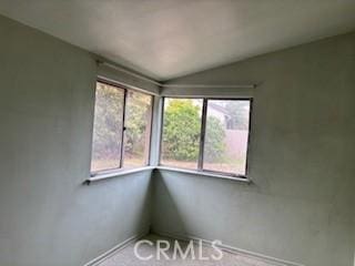 spare room featuring baseboards and vaulted ceiling