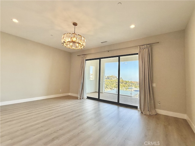 spare room with visible vents, baseboards, light wood finished floors, an inviting chandelier, and recessed lighting