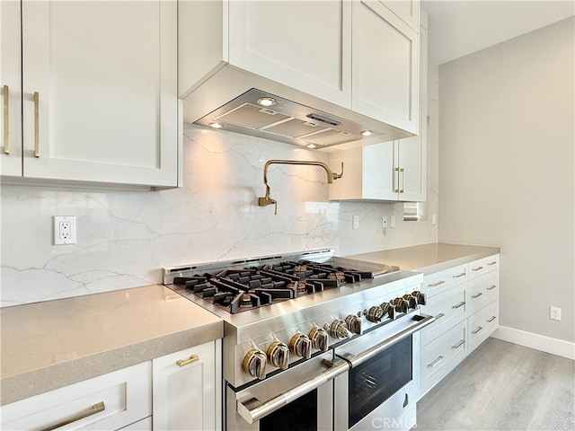 kitchen featuring light wood-style flooring, white cabinetry, decorative backsplash, and range with two ovens