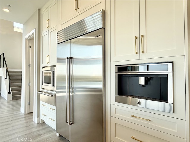 kitchen featuring built in appliances, light wood-style floors, recessed lighting, white cabinets, and a warming drawer