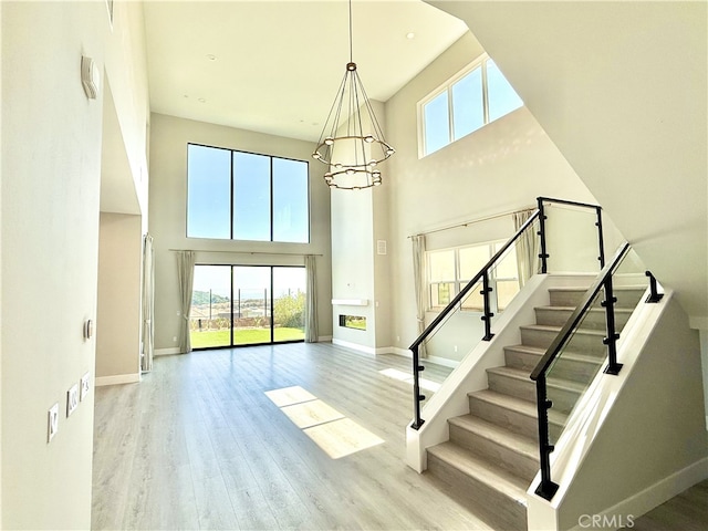 stairs with a high ceiling, a wealth of natural light, and wood finished floors