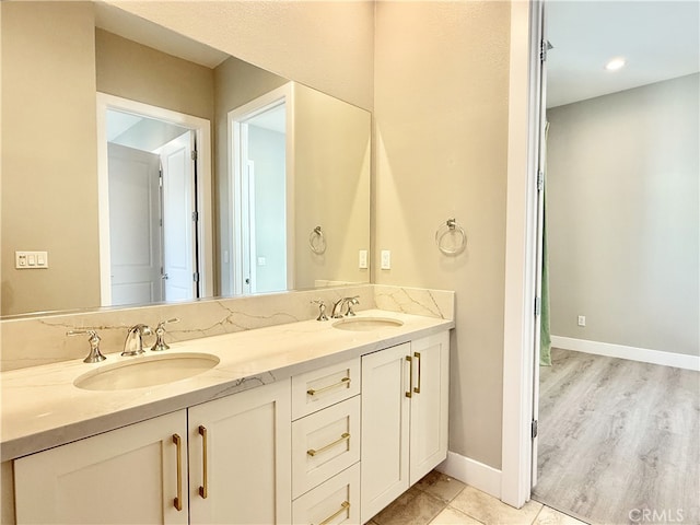 bathroom with double vanity, baseboards, and a sink