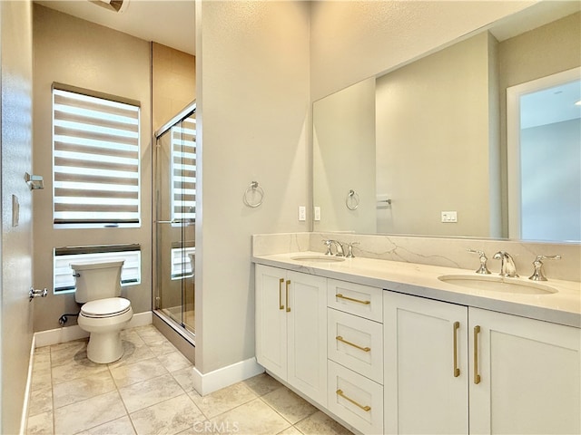 full bath featuring a sink, double vanity, toilet, a shower stall, and a wealth of natural light