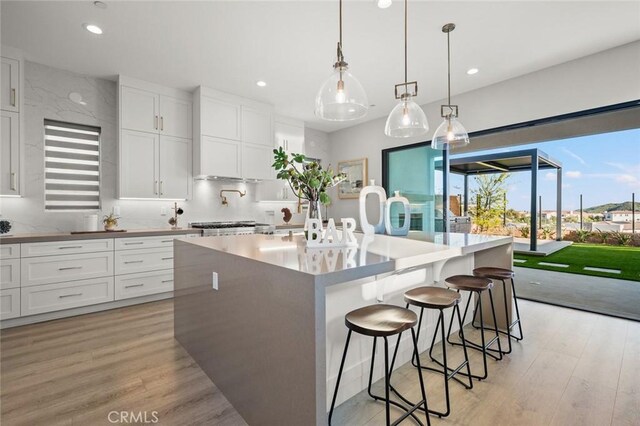 20526 W Overlook Ct, Porter Ranch, CA 91326 - kitchen with light wood-style flooring, a kitchen island with sink, white cabinetry, recessed lighting, and a breakfast bar
