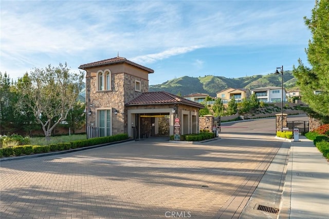 20526 W Overlook Ct, Porter Ranch, CA 91326 - view of front of property featuring stone siding, a gate, a mountain view, decorative driveway, and a tile roof