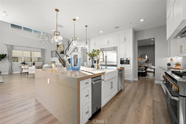 20526 W Overlook Ct, Porter Ranch, CA 91326 - kitchen with range with two ovens, light wood-style flooring, a sink, an island with sink, and recessed lighting