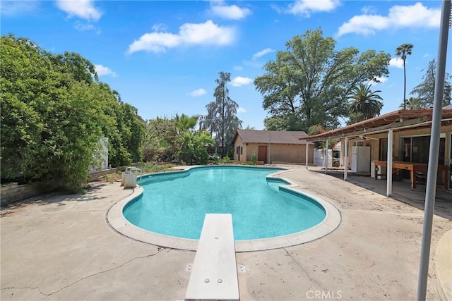 outdoor pool featuring a diving board and a patio area