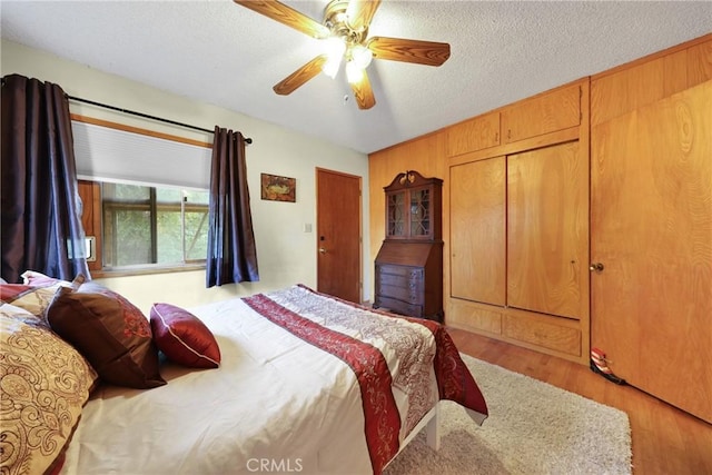 bedroom with a textured ceiling, ceiling fan, and wood finished floors