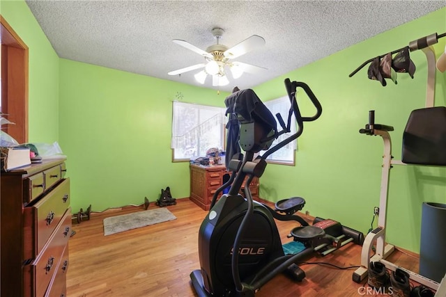 exercise area featuring a textured ceiling, light wood-style flooring, and ceiling fan