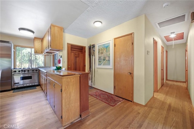 kitchen with light wood-style flooring, a peninsula, and high end appliances