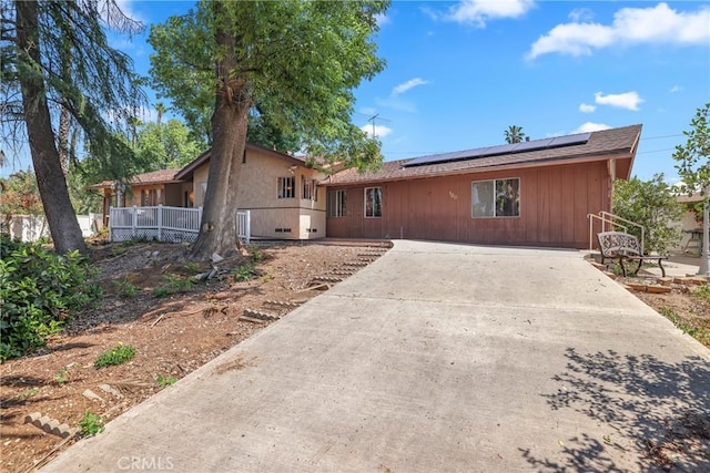 view of front of property featuring concrete driveway and solar panels