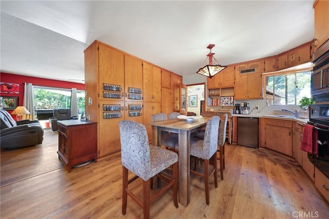 kitchen with stainless steel dishwasher, a sink, light wood-style flooring, and visible vents