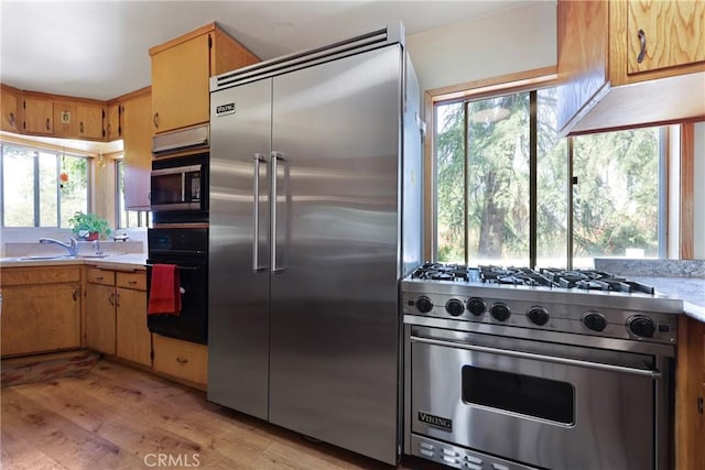 kitchen featuring light countertops, light wood finished floors, a wealth of natural light, and high quality appliances
