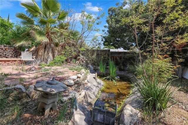 view of yard with a fenced backyard and a small pond
