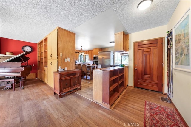 kitchen featuring open shelves, built in fridge, and light wood-style floors