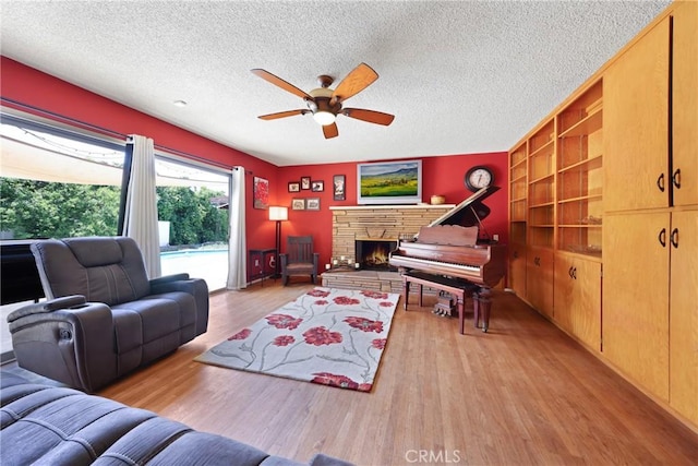 living room featuring a textured ceiling, ceiling fan, and wood finished floors