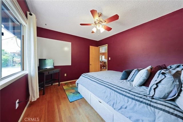 bedroom featuring a textured ceiling, baseboards, a ceiling fan, and wood finished floors