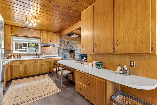 kitchen featuring light countertops, dark tile patterned floors, visible vents, and wooden ceiling