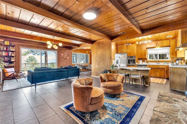 living area featuring wooden walls, a chandelier, plenty of natural light, wooden ceiling, and beamed ceiling