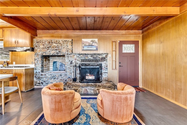 living area with wooden walls, beamed ceiling, wood ceiling, and a fireplace