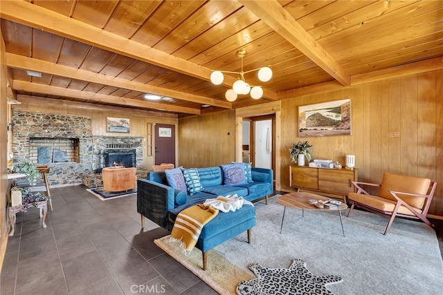 living area with wooden walls, wooden ceiling, a stone fireplace, and beam ceiling