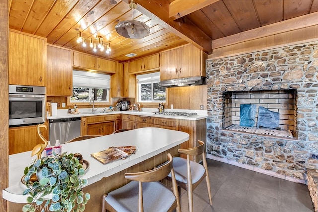 kitchen featuring a sink, light countertops, stainless steel appliances, wooden ceiling, and under cabinet range hood