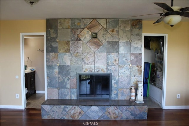 room details with baseboards, a ceiling fan, wood finished floors, and a fireplace